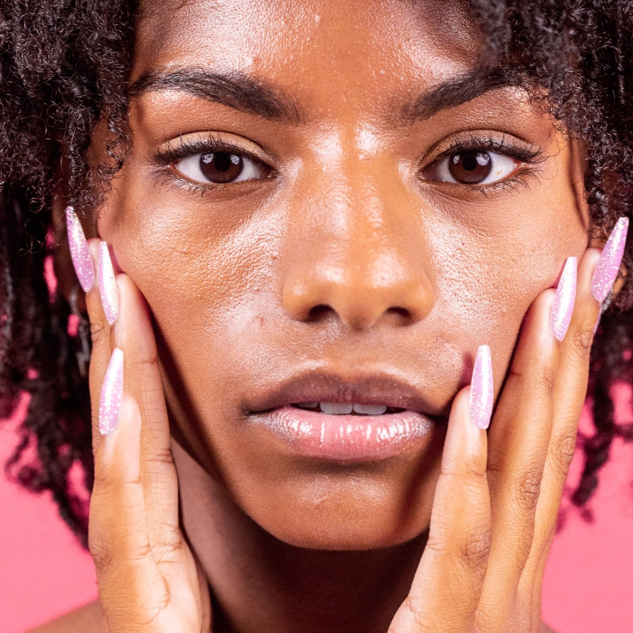 Girl with hands on face, wearing pink glitter press-on nails by Instant Mani co. 