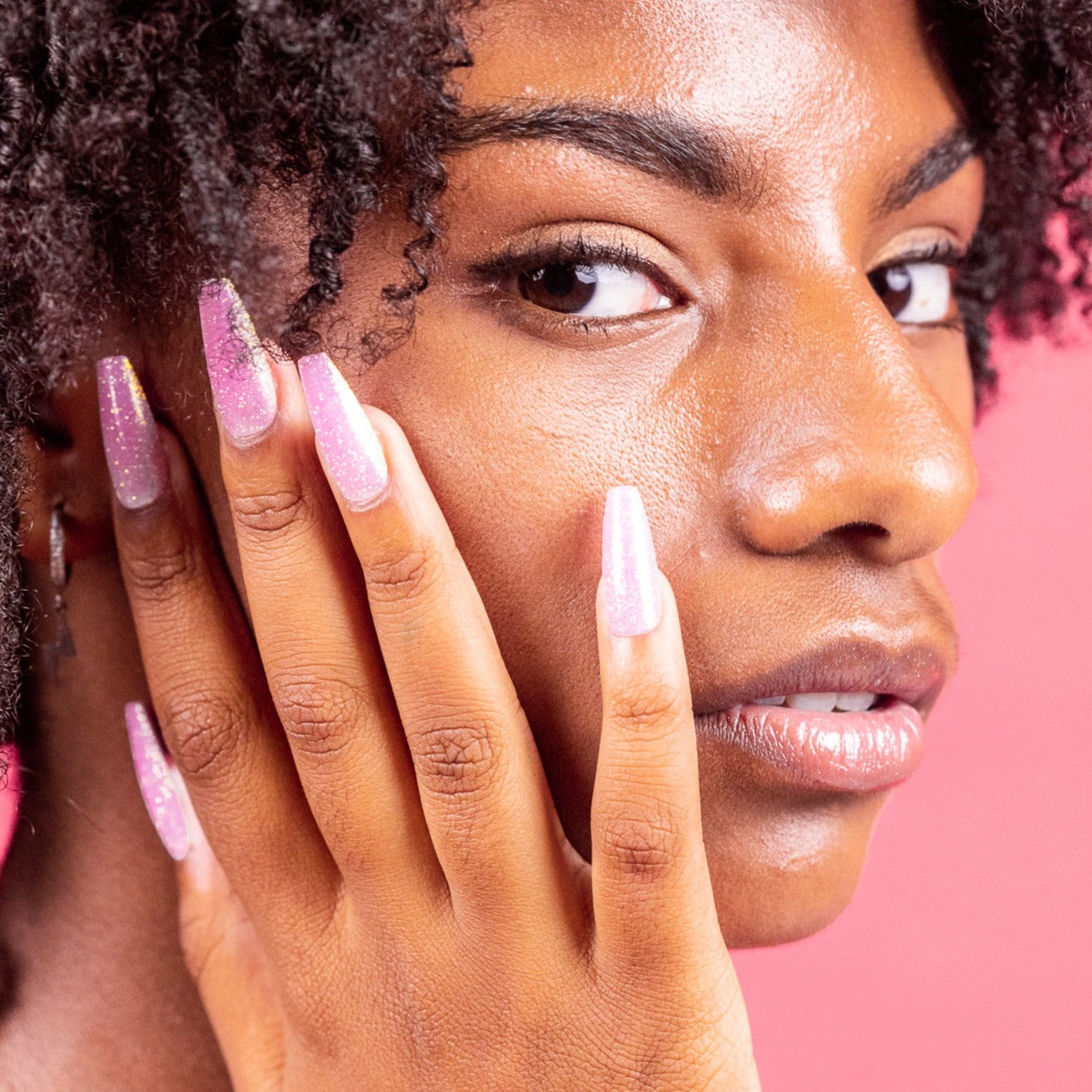 Girl with hand on face, wearing pink glitter Instant Mani Co. press-on nails 